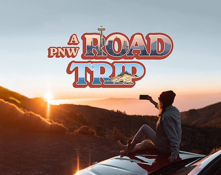 A person sitting on a car roof takes a selfie against a sunset over mountains. Text overlay: "A PNW Road Trip." The scene feels adventurous and serene.