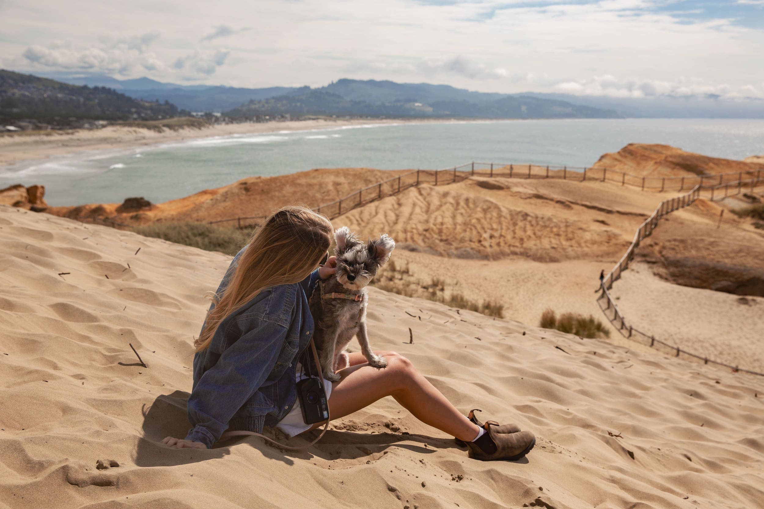 A woman and her dog sitting on the sand dunes at Inn at Cape Kiwanda