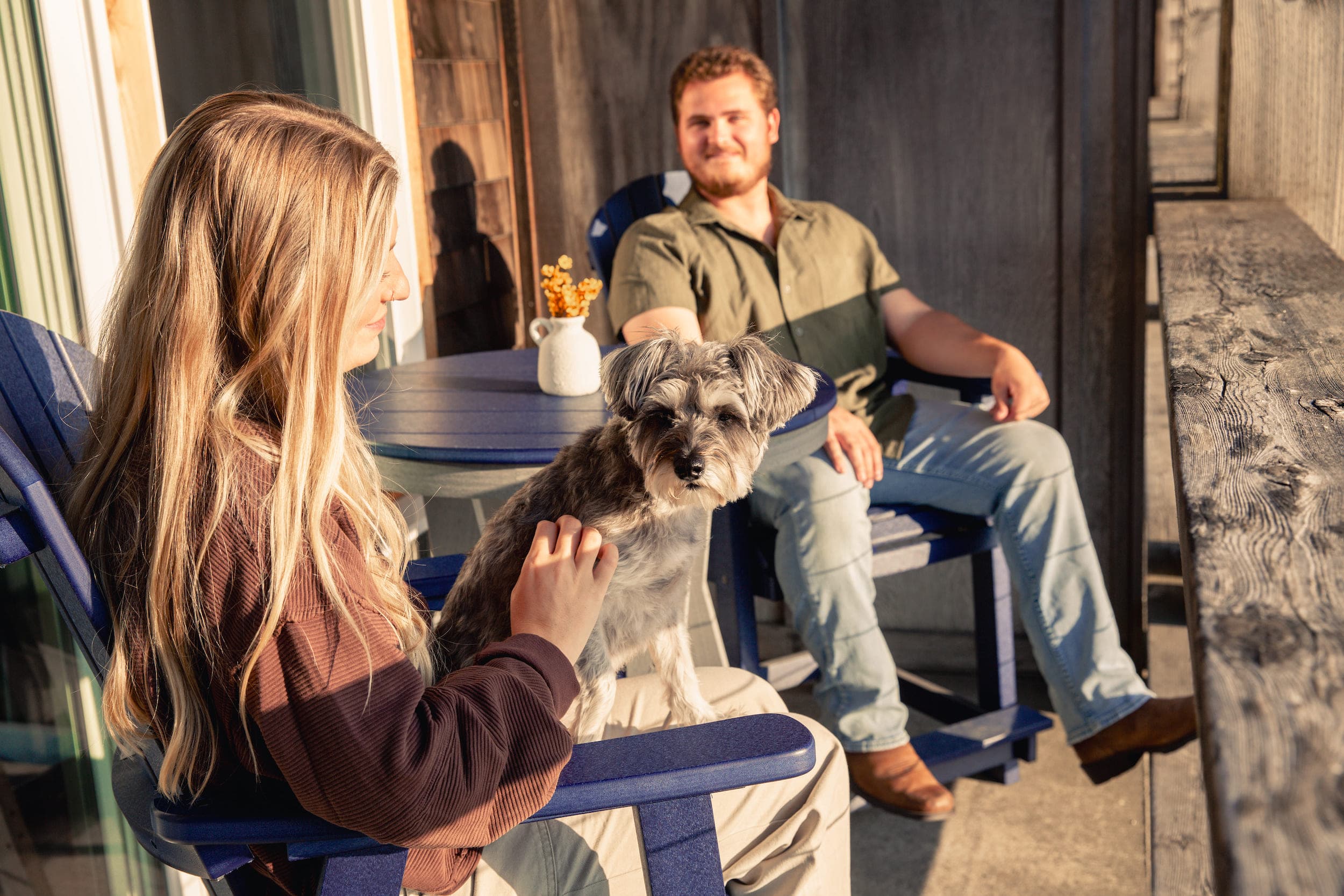 Two people sitting on a balcony of their room with their dog at Inn at Cape Kiwanda
