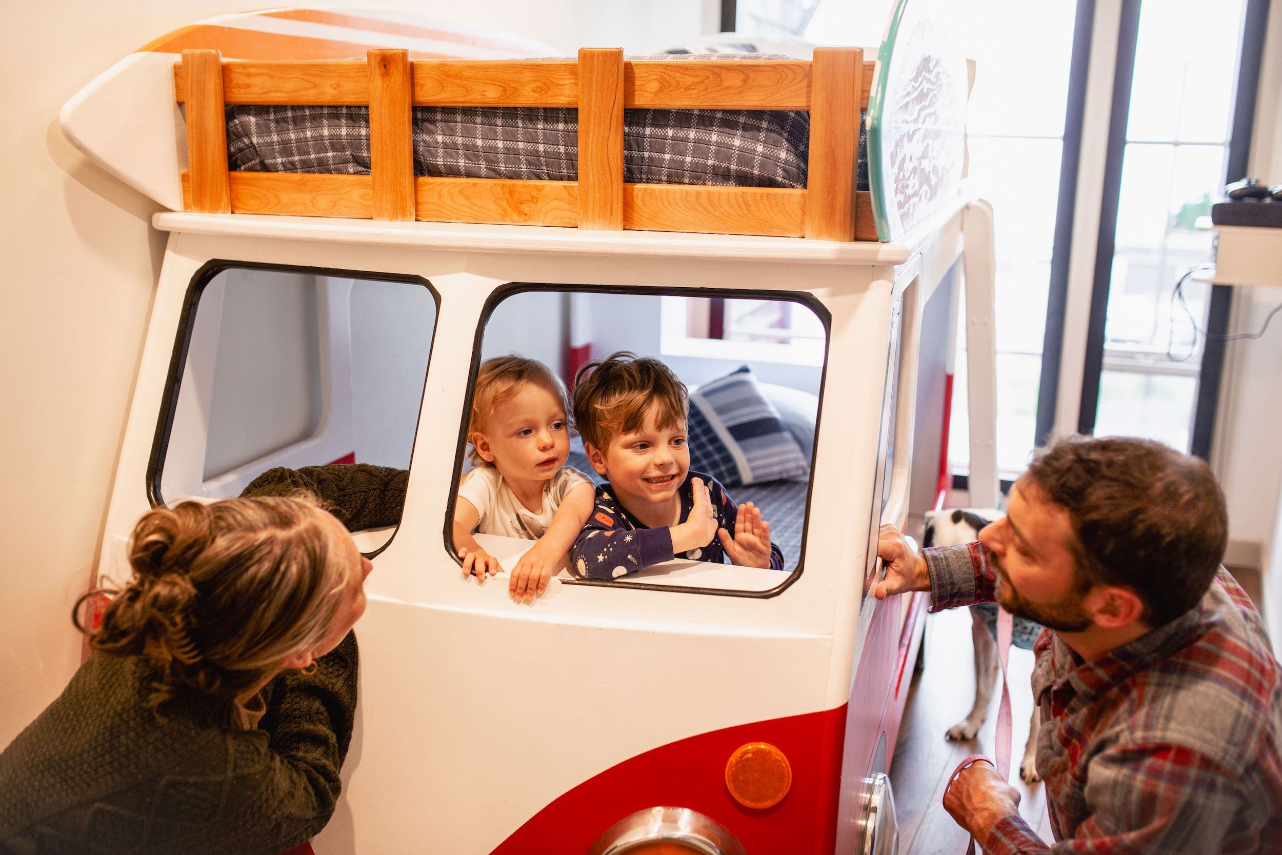 Two kids inside the VW bunk bed playing with their parents in a bunk room at Inn at Cape Kiwanda