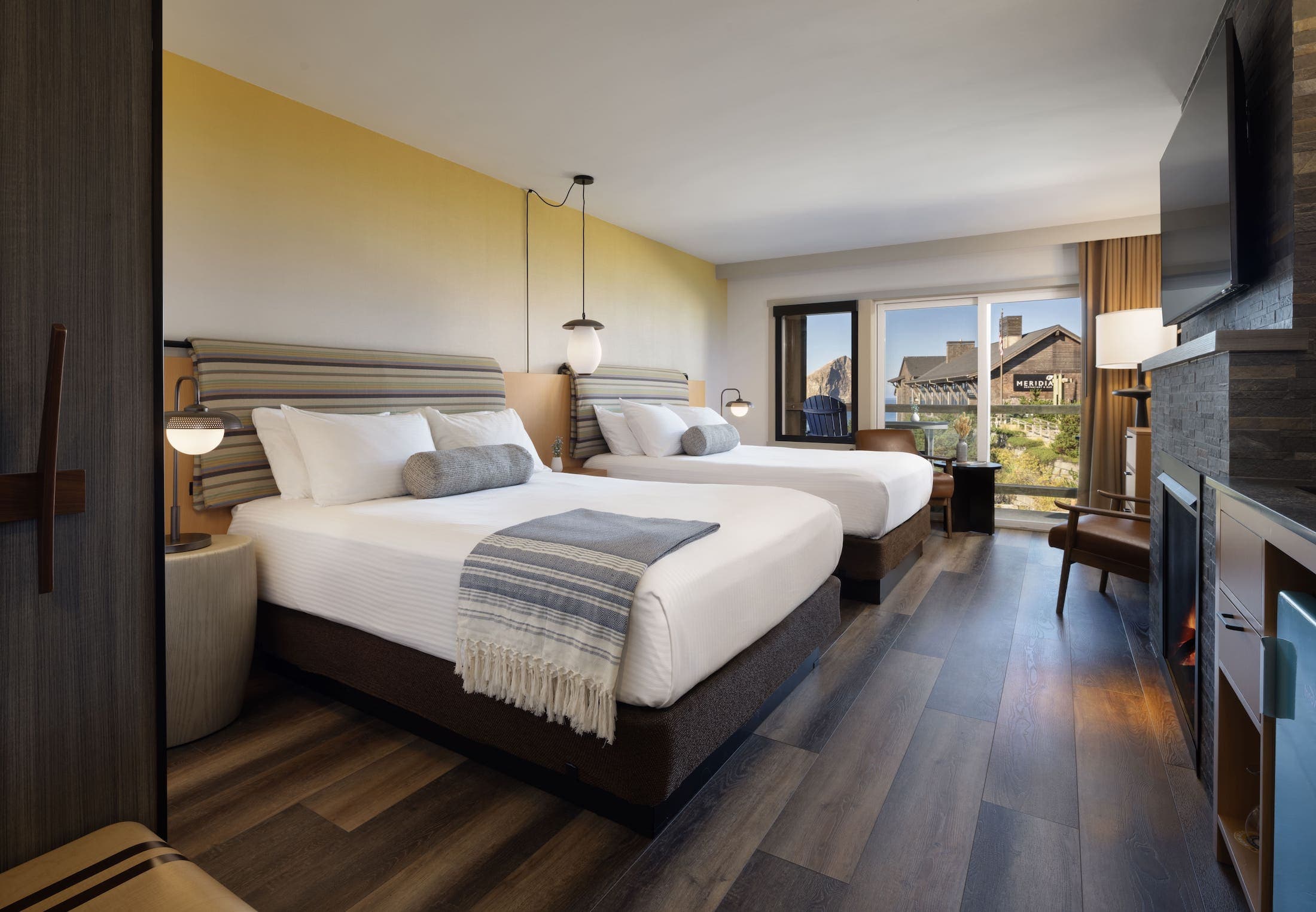 Inn At Cape Kiwanda Top Floor Two Queens Accessible room with a fireplace, lounge chairs, and a balcony