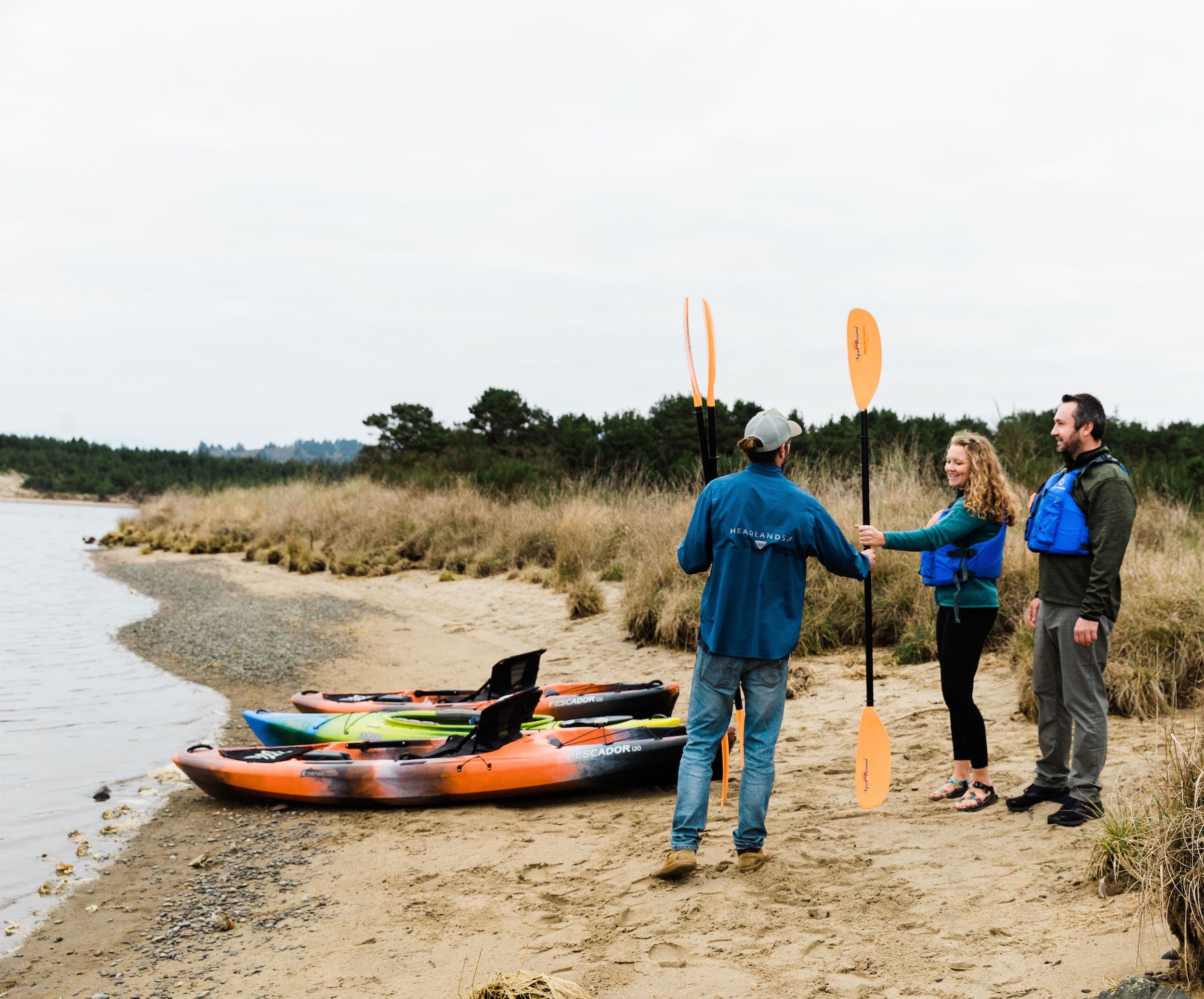 Three people getting ready to kayak on the ocean