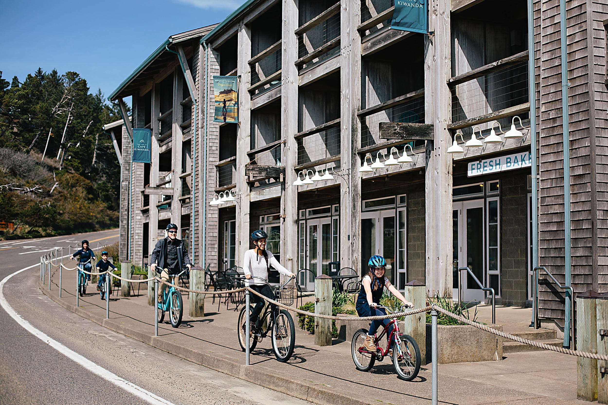 Family bike riding past the Inn at Cape Kiwanda in Pacific City on the Oregon Coast